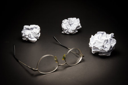 Glasses crumpled paper on black background. Business frustrations, Job stress and Failed exam...