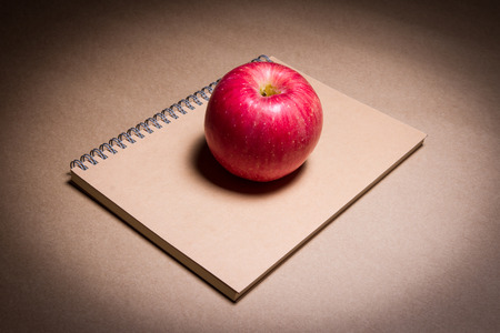 an apple on a brown notebookの写真素材