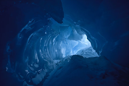 blue ice cave covered with snow and flooded with light