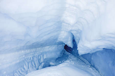 blue ice cave covered with snow and flooded with lightの写真素材
