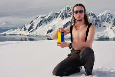 Man on top of the mountain holding a white form. Antarctica.