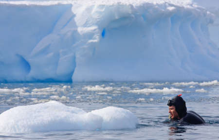 Diver on the ice against the blue iceberg. Antarcticaの写真素材