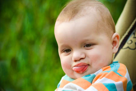 Cute kid on a green background showing a tongueの写真素材