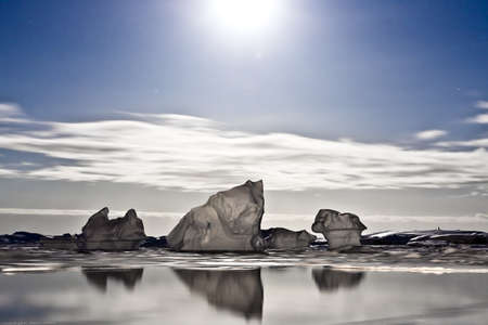Summer night in Antarctica.Icebergs floating in the moonlightの写真素材