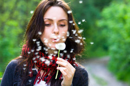 Girl blowing on white dandelion in the forestの写真素材