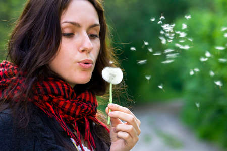 Girl blowing on white dandelion in the forestの写真素材