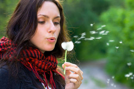 Girl blowing on white dandelion in the forestの写真素材