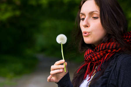 Girl blowing on white dandelion in the forestの写真素材