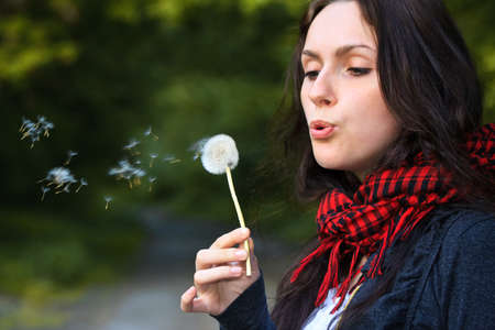 Girl blowing on white dandelion in the forestの写真素材