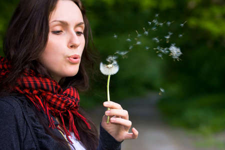Girl blowing on white dandelion in the forestの写真素材