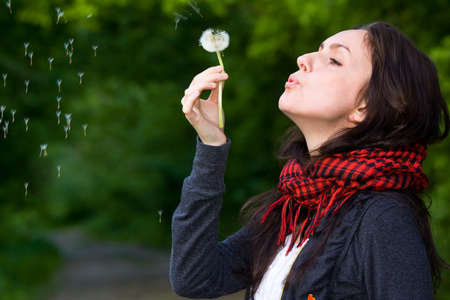 Girl blowing on white dandelion in the forestの写真素材
