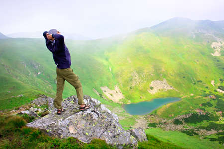 Beautiful mountains landscape with lake  in Carpathian mountains and man on the topの写真素材