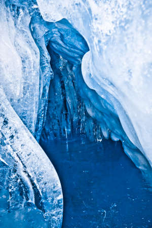 blue ice cave covered with snow and flooded with lightの写真素材