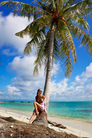 Beautiful woman relaxes near the tree in paradiseの写真素材