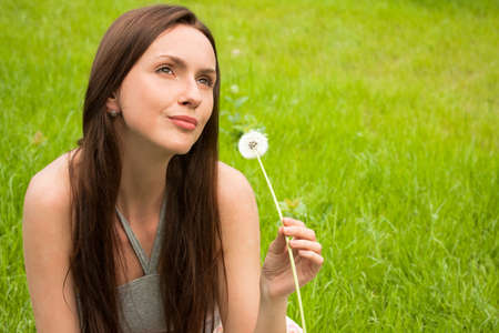 Girl with dandelion on green fieldの写真素材