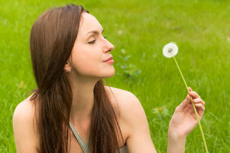 Girl with dandelion on green fieldの写真素材