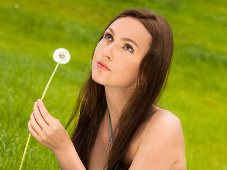 Girl with dandelion on green fieldの写真素材
