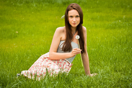 Girl with dandelion on green fieldの写真素材