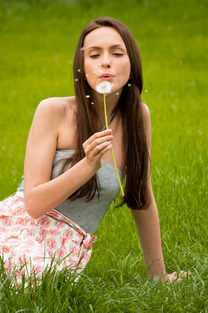 Girl with dandelion on green fieldの写真素材
