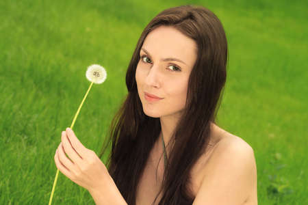 Girl with dandelion on green fieldの写真素材