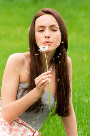 Girl with dandelion on the green fieldの写真素材