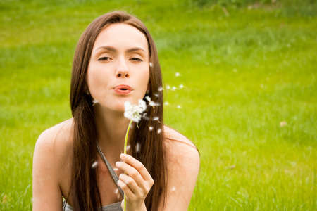 Girl with dandelion on green fieldの写真素材