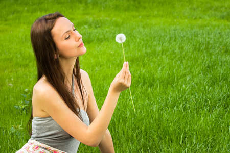 Girl with dandelion on the green fieldの写真素材