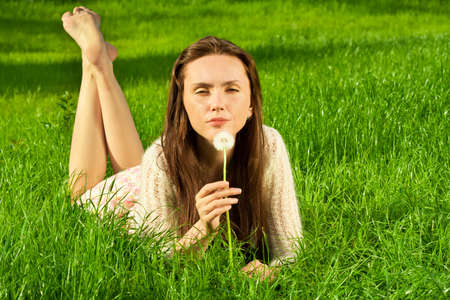 Girl with dandelion on the green fieldの写真素材