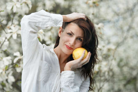 Beautiful young girl eating an apple in the parkの写真素材