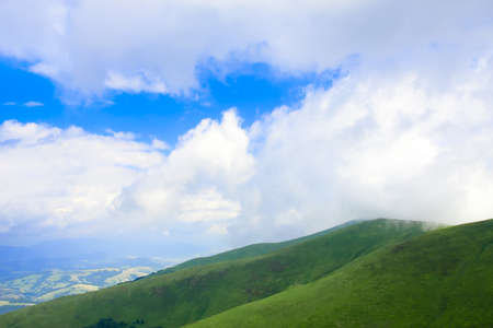 Blue cloudy sky and green spring hillの写真素材