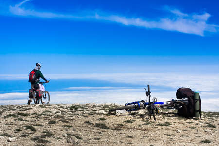 Young man riding a bike over the precipice in the mountainsの写真素材