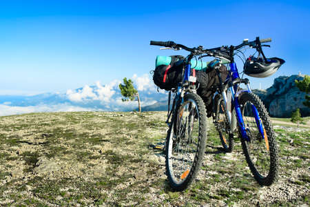 two bikes on the precipice, sky and mountains in the backgroundの写真素材