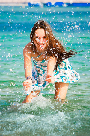 Beautiful young girl splashing the water in the seaの写真素材