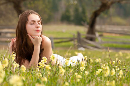 Young woman lying on field dreaming summer dayの写真素材