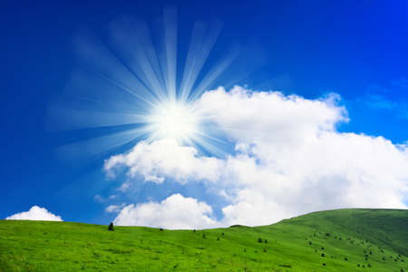 Blue cloudy sky and green spring hillの写真素材