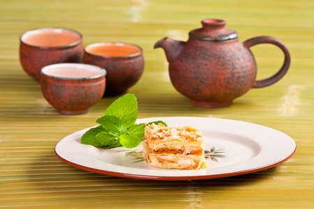 napoleon cake on white plate with cups for teaの写真素材