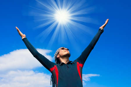 young active man standing on the background of blue skyの写真素材