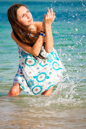 Beautiful young girl splashing the water in the seaの写真素材