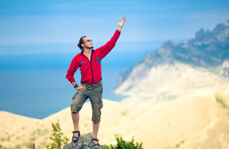 Man on top of mountain holding arm upの写真素材