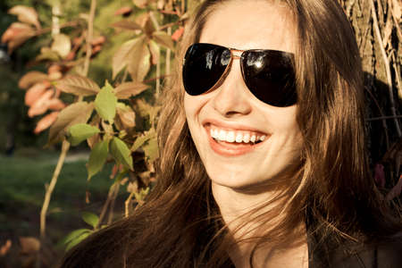 Beautiful girl smiling at the background of the autumn woodsの写真素材