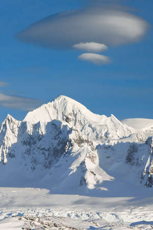 mountain peak is covered with white snow on a sunny day in Antarcticaの写真素材