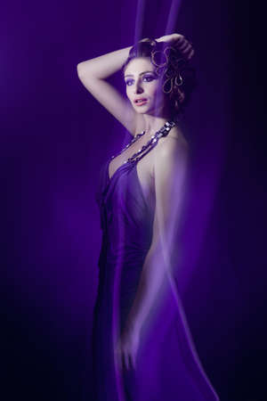 beautiful young woman in evening dress in violet lightの写真素材