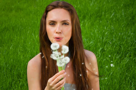 Girl with dandelion on green fieldの写真素材
