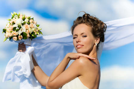 Portrait of a young bride in a white dress with a bouquet of flowersの写真素材