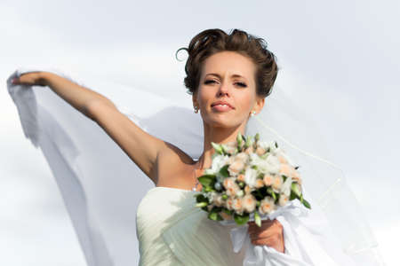 Portrait of a young bride in a white dress with a bouquet of flowersの写真素材