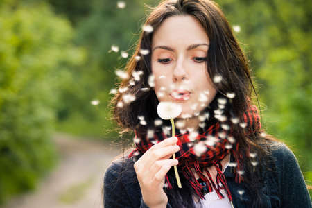 Girl blowing on white dandelion in the forestの写真素材