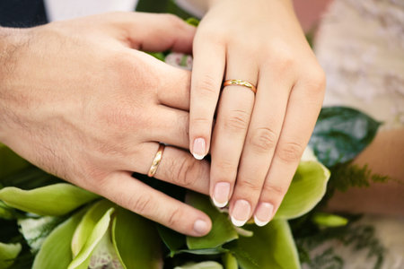 Bride and groom holding hands with wedding rings