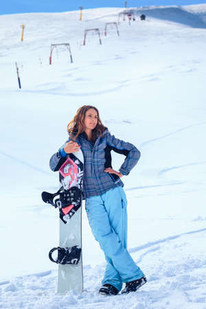 young snowboarder girl in winter clothes with snowboard in her handsの写真素材