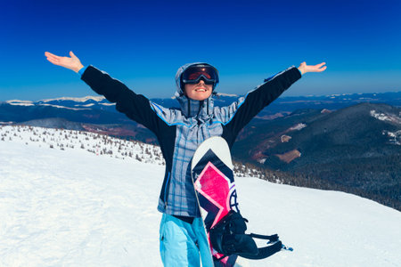 young snowboarder girl in winter clothes with snowboard in her handsの写真素材