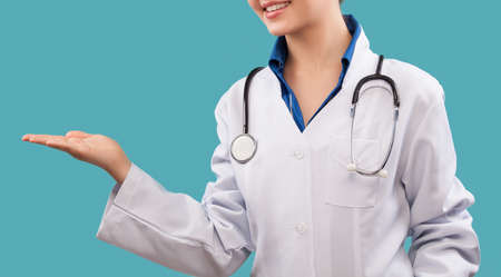Friendly female doctor - isolated over a blue backgroundの写真素材